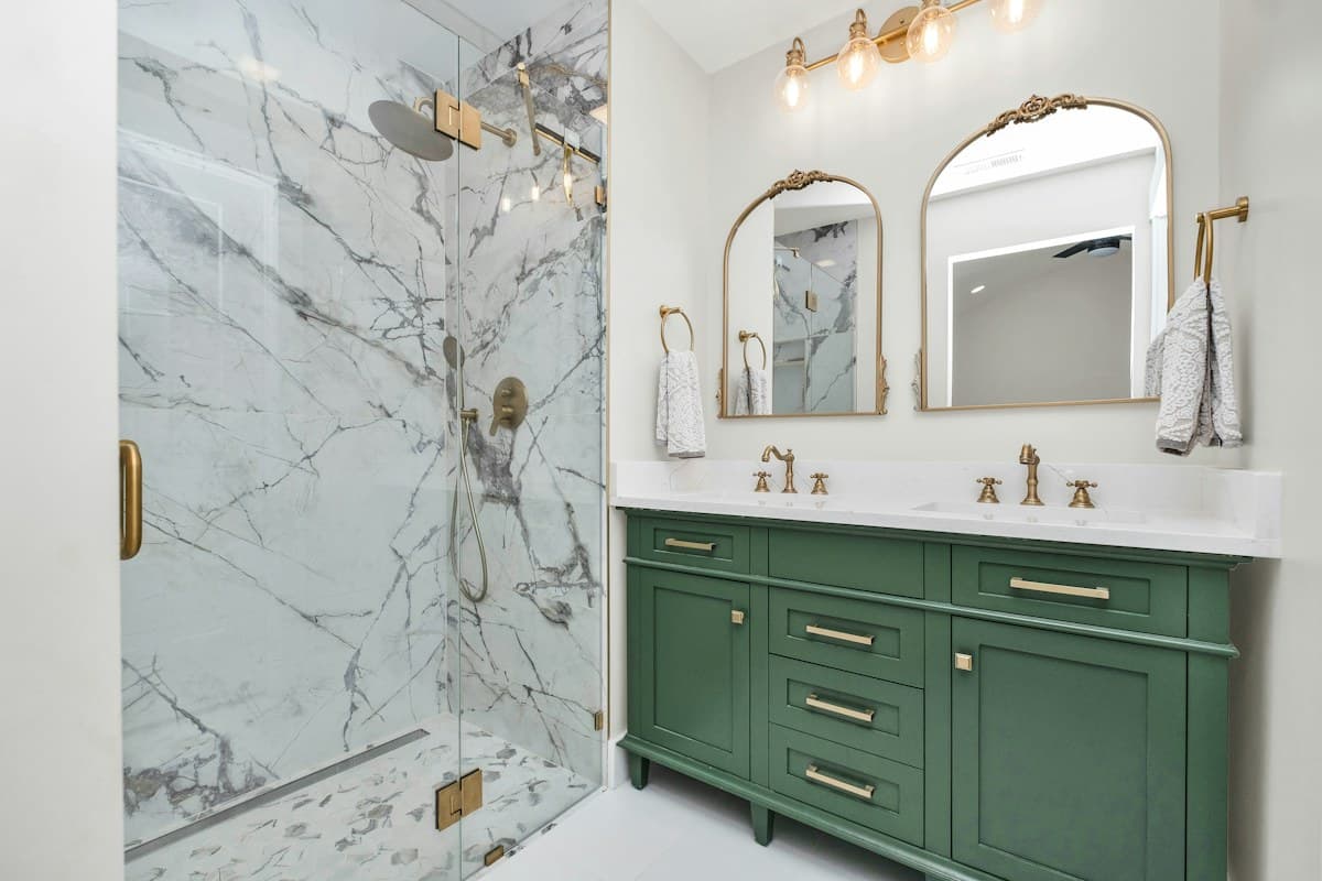 Bathroom with a marble shower, green vanity and gold taps